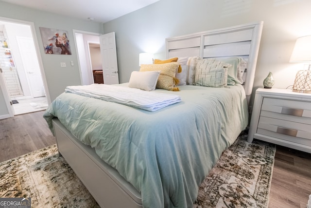 bedroom featuring ensuite bathroom and wood finished floors