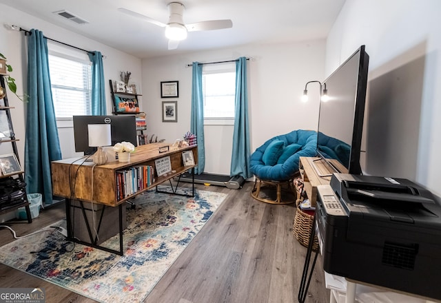 home office featuring plenty of natural light, visible vents, ceiling fan, and wood finished floors