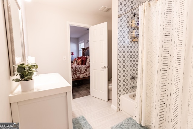 bathroom featuring toilet, shower / tub combo, connected bathroom, vanity, and wood finished floors