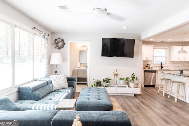 living room with a wealth of natural light, ceiling fan, sink, and light hardwood / wood-style floors