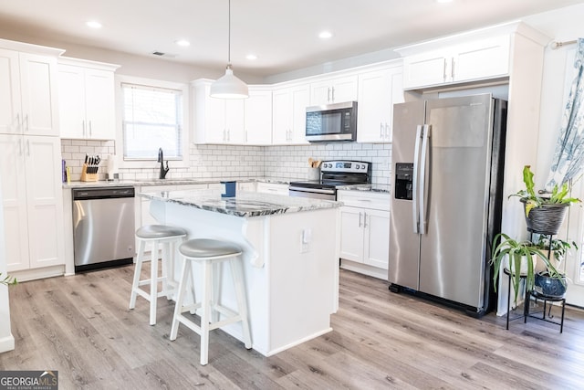 kitchen with light wood finished floors, stainless steel appliances, visible vents, a sink, and a kitchen island