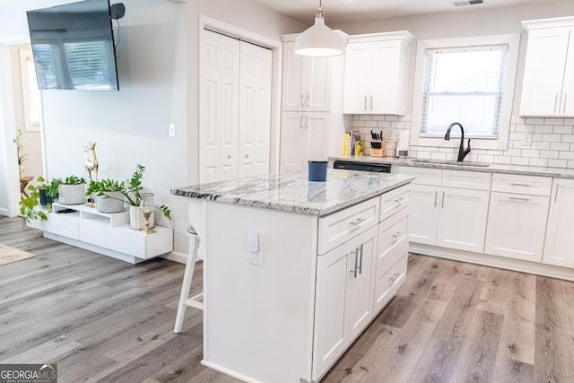 kitchen with backsplash, a sink, and light wood-style flooring