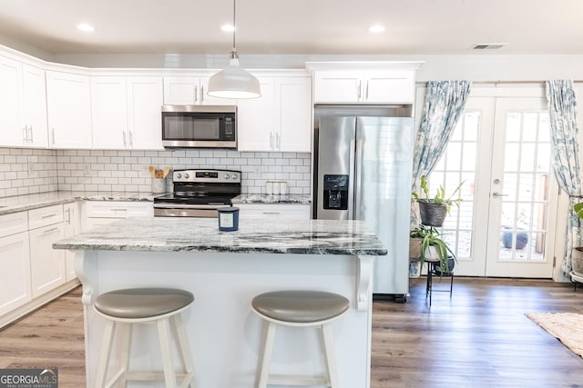 kitchen with light wood finished floors, visible vents, a kitchen bar, and appliances with stainless steel finishes