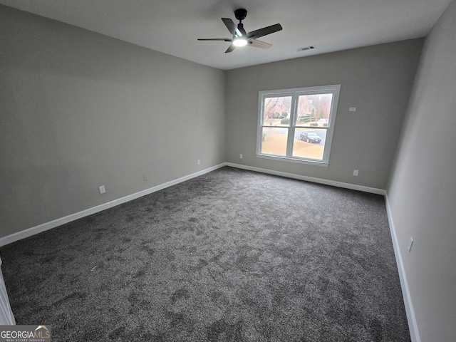 spare room featuring dark carpet and ceiling fan