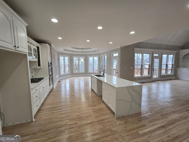 kitchen with white cabinets, light stone counters, sink, and light hardwood / wood-style flooring