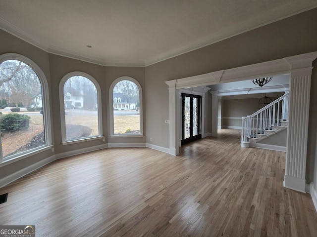 empty room with hardwood / wood-style floors, crown molding, and a notable chandelier