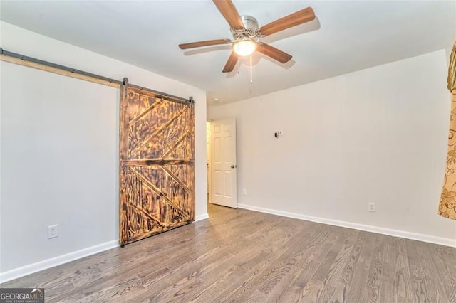 spare room with hardwood / wood-style floors, a barn door, and ceiling fan