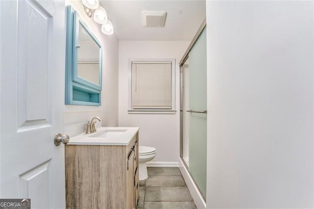 bathroom with tile patterned floors, vanity, an enclosed shower, and toilet