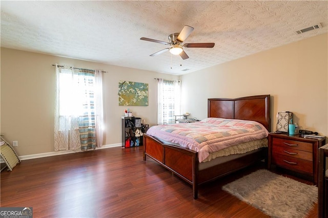 bedroom featuring ceiling fan, dark wood-type flooring, and a textured ceiling