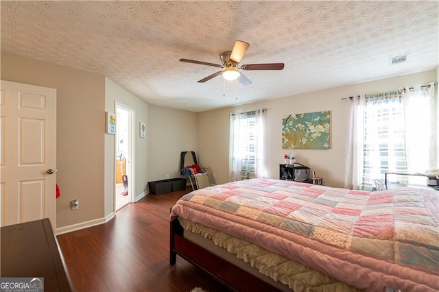 bedroom featuring ceiling fan, dark hardwood / wood-style flooring, and a textured ceiling