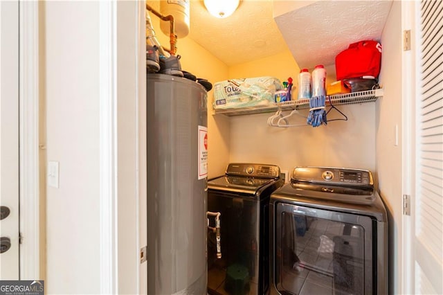 laundry room featuring washing machine and clothes dryer, a textured ceiling, and water heater