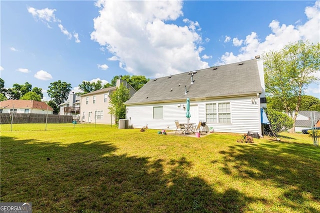 back of property with central AC and a lawn