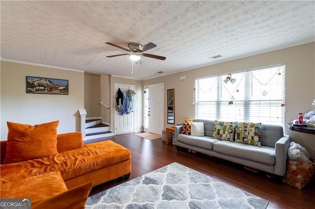 living room with dark hardwood / wood-style floors, ceiling fan, ornamental molding, and a textured ceiling