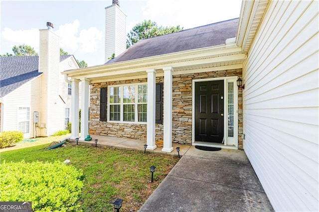 doorway to property with covered porch and a yard