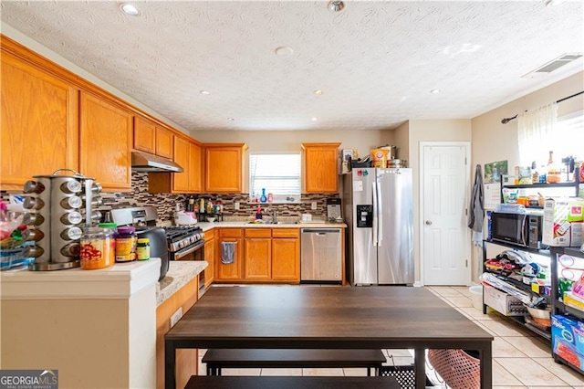 kitchen with sink, light tile patterned floors, stainless steel appliances, and a textured ceiling