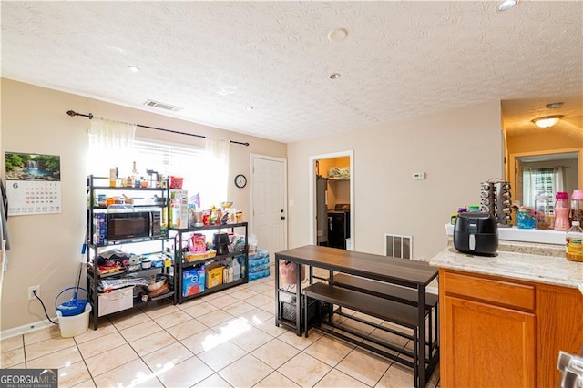 kitchen featuring light stone countertops, light tile patterned floors, and a textured ceiling