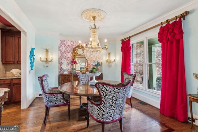 dining room with dark wood-type flooring, an inviting chandelier, and crown molding