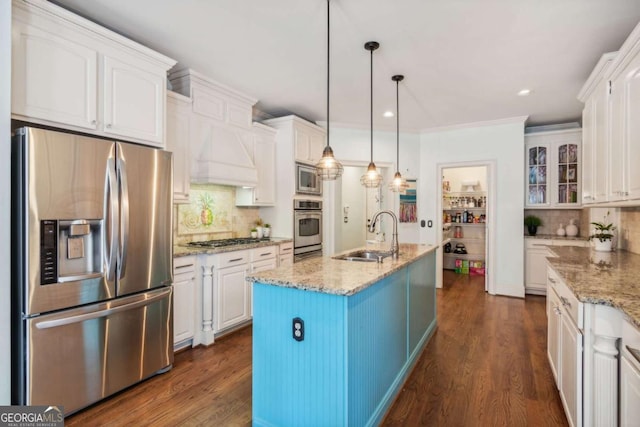 kitchen featuring decorative backsplash, stainless steel appliances, sink, white cabinets, and an island with sink