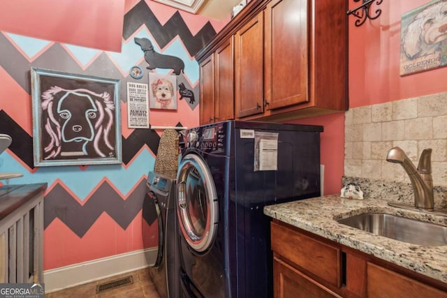 clothes washing area featuring tile patterned floors, cabinets, and sink