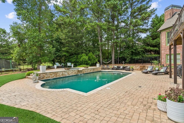 view of swimming pool with a patio and a trampoline