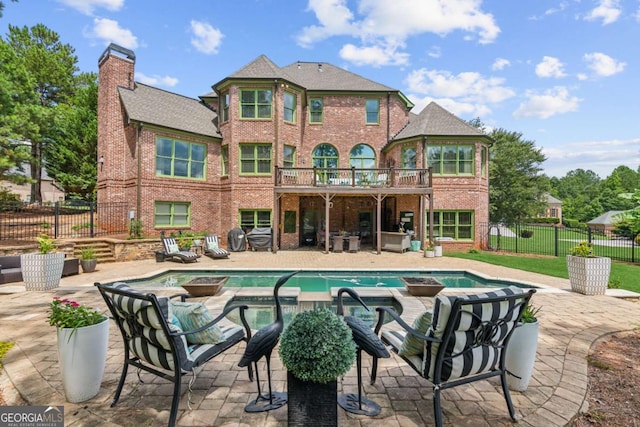 back of property with a patio area and a pool with hot tub