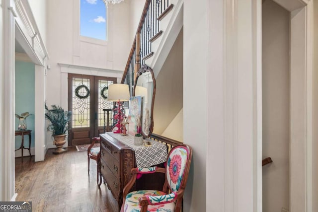 foyer with french doors, a towering ceiling, and wood-type flooring