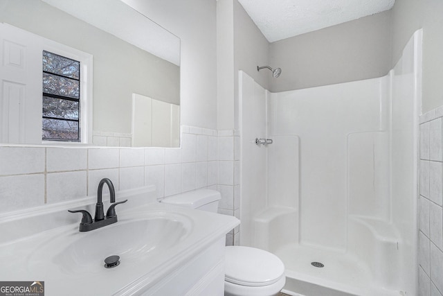 bathroom featuring a textured ceiling, toilet, tile walls, and walk in shower