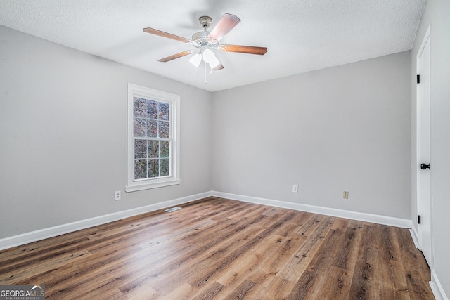 empty room with ceiling fan, dark wood-type flooring, and a textured ceiling