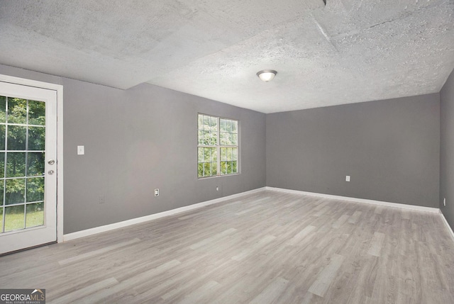 empty room with light hardwood / wood-style flooring and a textured ceiling