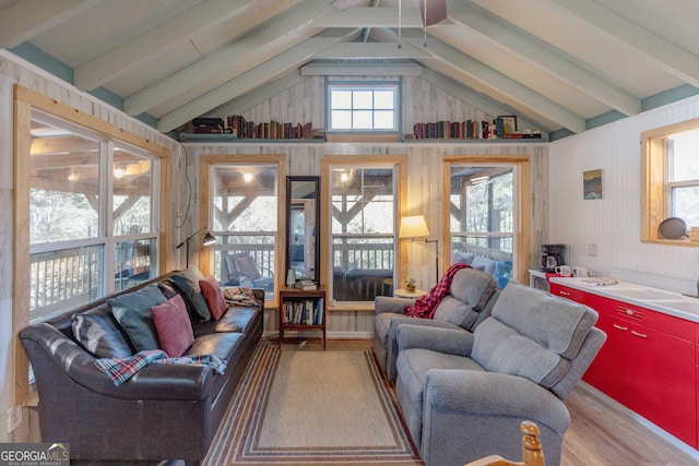 living room with a healthy amount of sunlight, lofted ceiling with beams, and light hardwood / wood-style floors