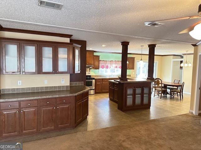 kitchen featuring pendant lighting, ceiling fan with notable chandelier, stainless steel stove, a textured ceiling, and a kitchen island