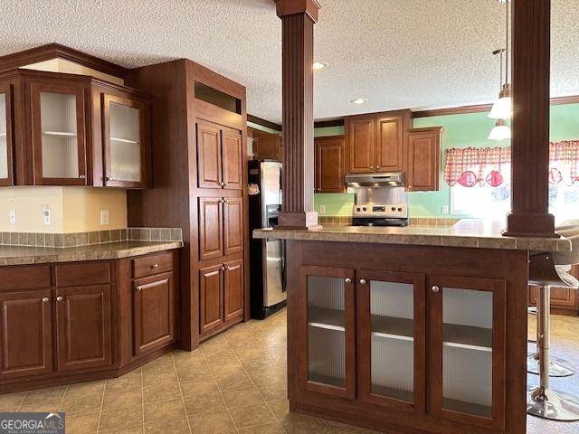 kitchen with a kitchen bar, stove, a textured ceiling, and ornate columns