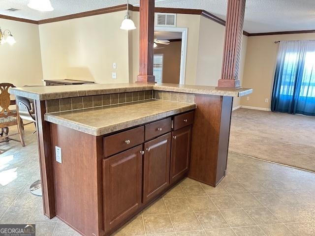 kitchen featuring a textured ceiling, ornate columns, and hanging light fixtures