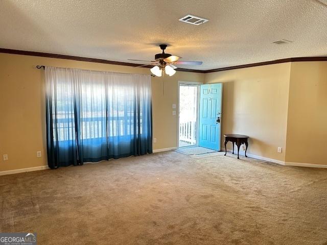 carpeted spare room with ceiling fan, crown molding, and a textured ceiling