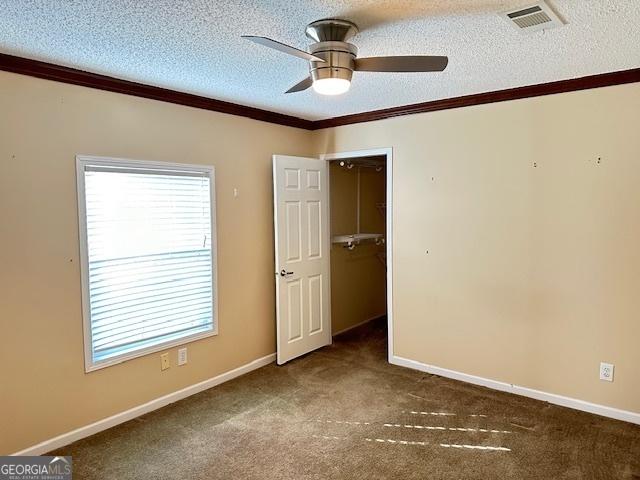 carpeted spare room with a textured ceiling, ceiling fan, and crown molding