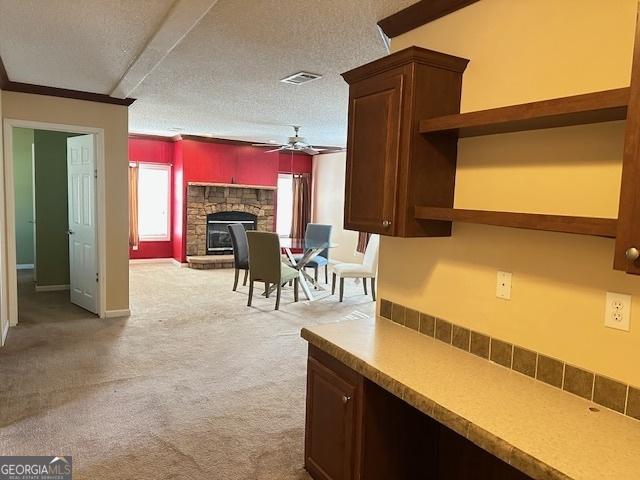 kitchen featuring a fireplace, a textured ceiling, ceiling fan, and a healthy amount of sunlight