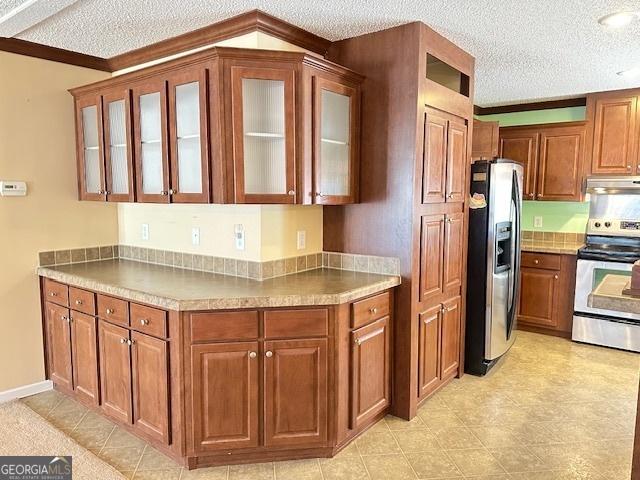 kitchen with appliances with stainless steel finishes, a textured ceiling, and ornamental molding