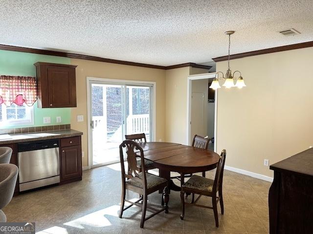 dining area with ornamental molding, a textured ceiling, and an inviting chandelier