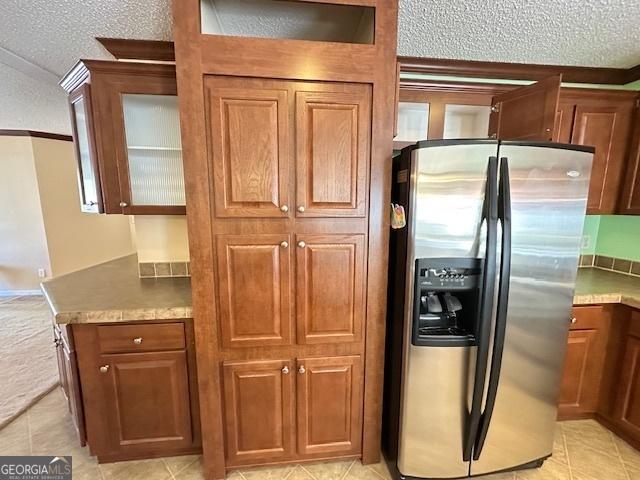 kitchen with stainless steel refrigerator with ice dispenser, a textured ceiling, lofted ceiling, and ornamental molding