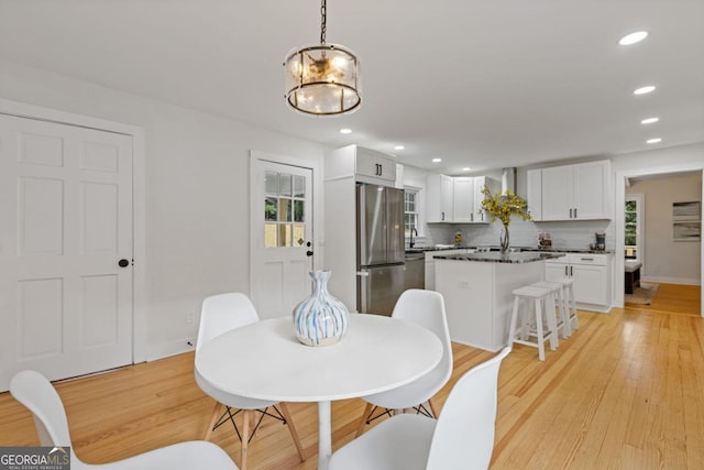 dining area featuring light wood-type flooring, a chandelier, and beam ceiling