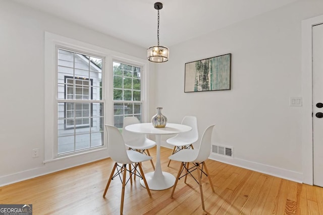 dining space featuring hardwood / wood-style flooring and an inviting chandelier