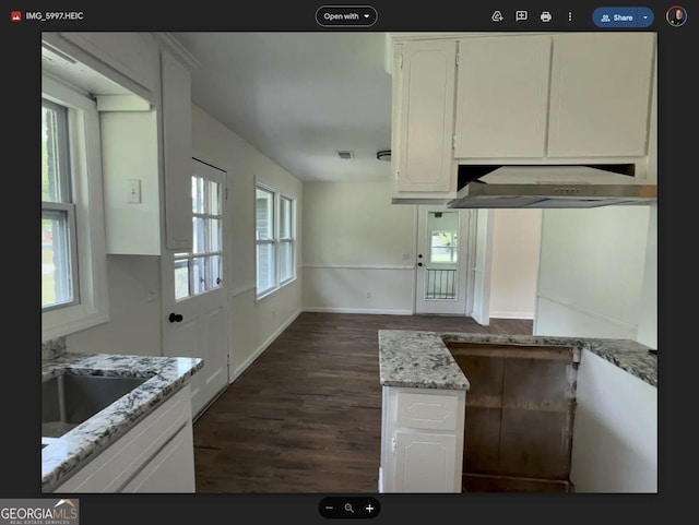 kitchen featuring dark hardwood / wood-style floors, light stone countertops, white cabinetry, and sink