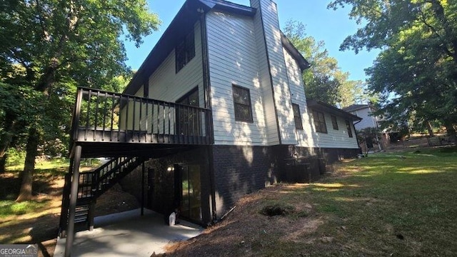 view of side of home with a lawn, central AC unit, and a deck