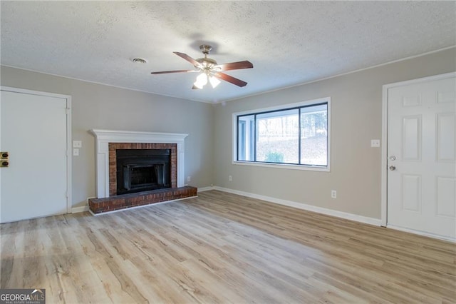 unfurnished living room featuring a textured ceiling, ceiling fan, light wood-type flooring, and a fireplace