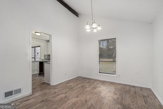 unfurnished room featuring lofted ceiling with beams, dark wood-type flooring, and an inviting chandelier