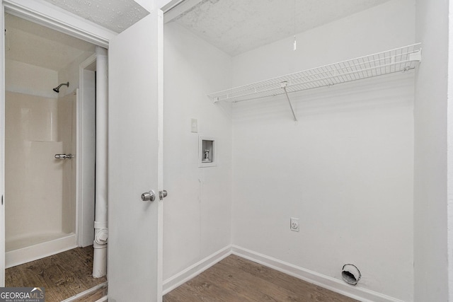 clothes washing area with electric dryer hookup, a textured ceiling, washer hookup, and dark hardwood / wood-style floors