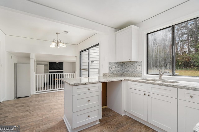 kitchen with white cabinetry, sink, tasteful backsplash, kitchen peninsula, and hardwood / wood-style flooring