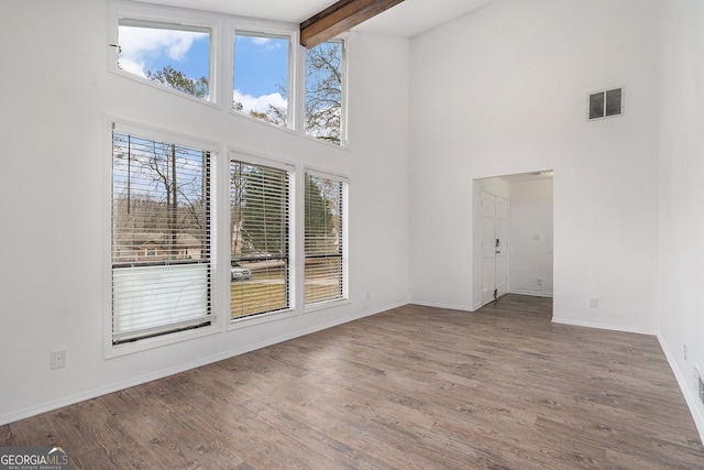 unfurnished room featuring beam ceiling, high vaulted ceiling, and wood-type flooring