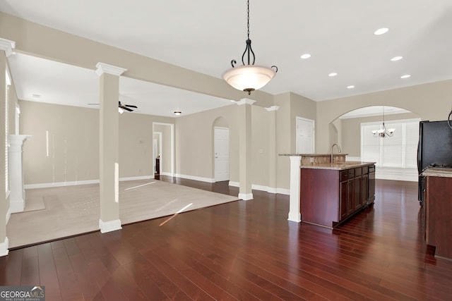 kitchen featuring light stone counters, sink, ceiling fan with notable chandelier, and decorative light fixtures