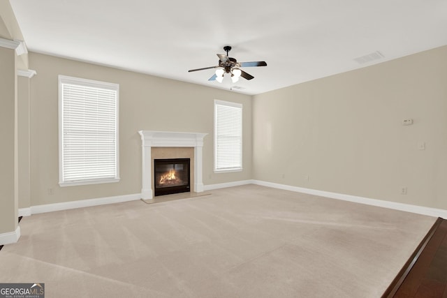 unfurnished living room with ceiling fan, light colored carpet, and a fireplace